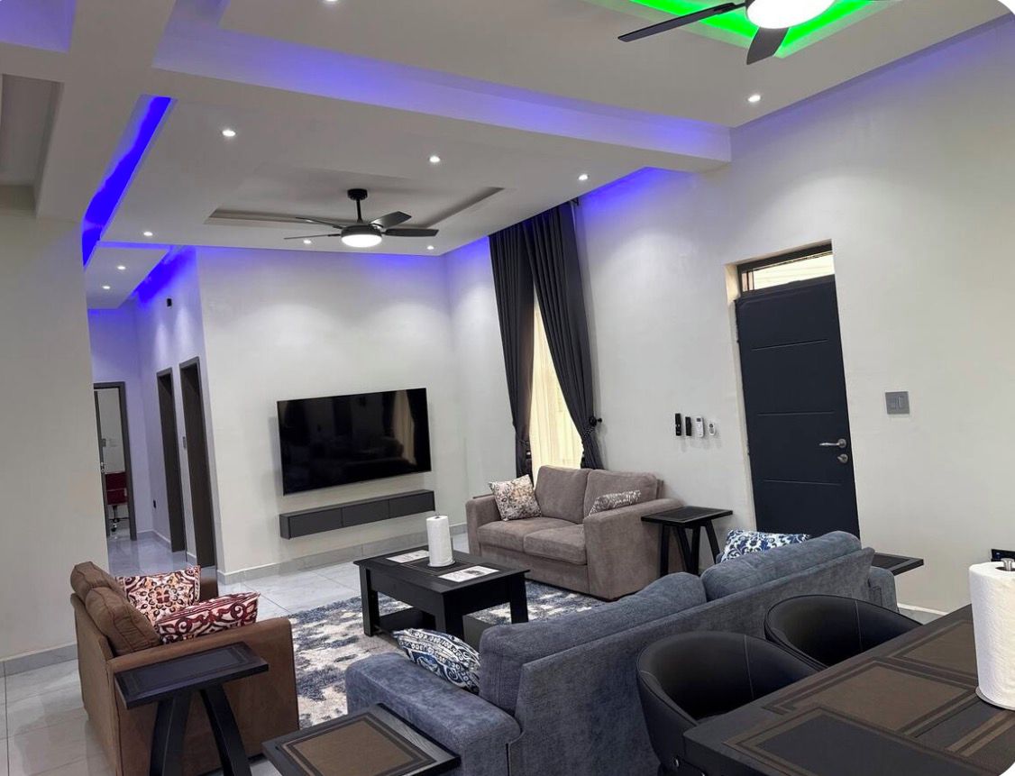A modern living room with a flat-screen TV, sofas, a coffee table, and a ceiling fan.