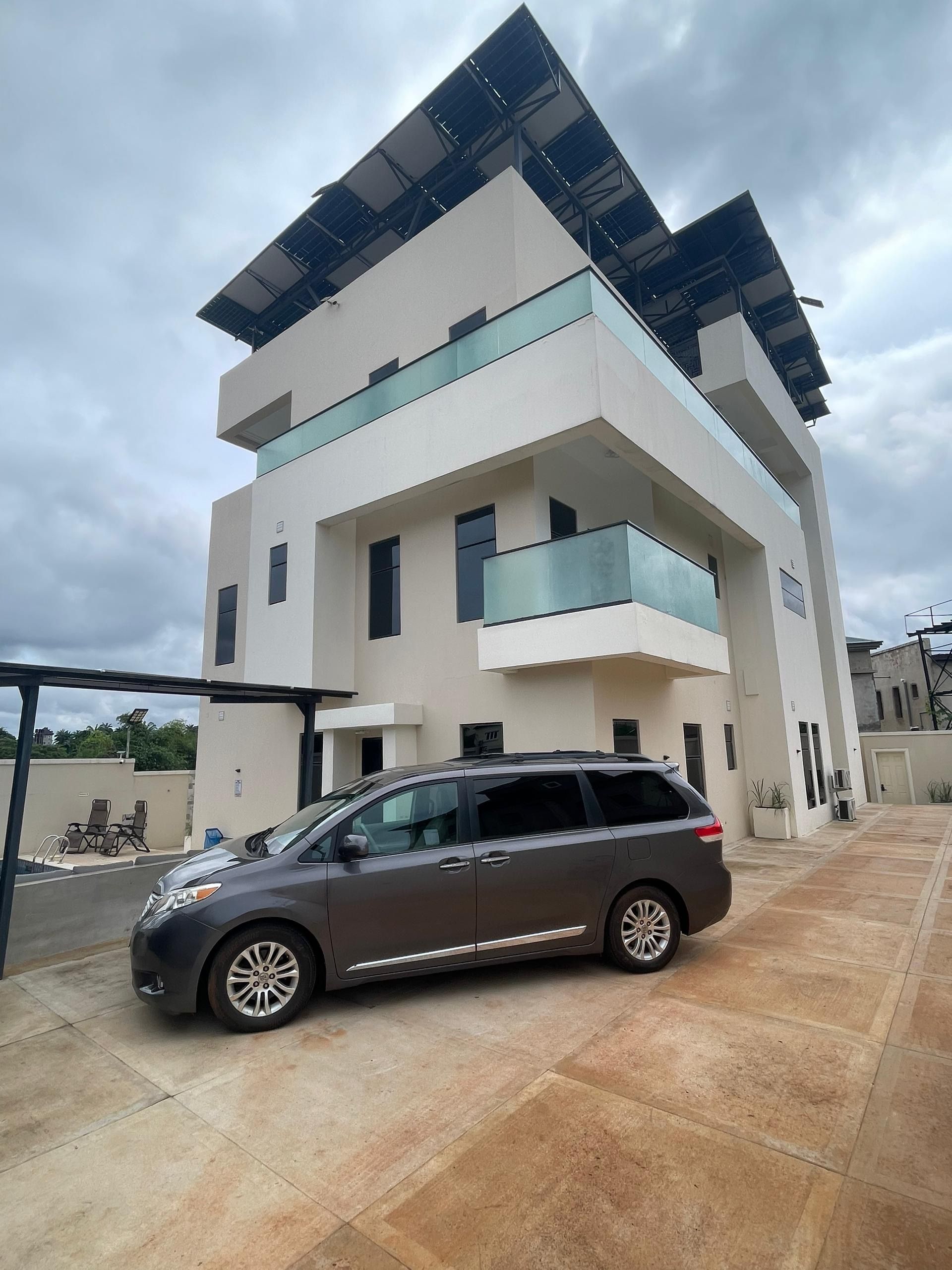 A modern multi-story building with a car parked in front.