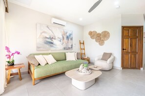 Ein modernes Wohnzimmer mit einem grünen Sofa, einem weißen Sessel und einem Couchtisch.