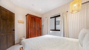 Une chambre à coucher avec un grand lit, une armoire en bois et une fenêtre avec des rideaux.