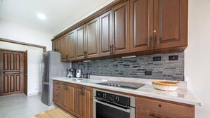 Une cuisine moderne avec des meubles en bois, un réfrigérateur en acier inoxydable, un four encastré et un pare-feu en pierre.