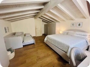 A bedroom with a large bed, a smaller bed, a wardrobe, and a door.