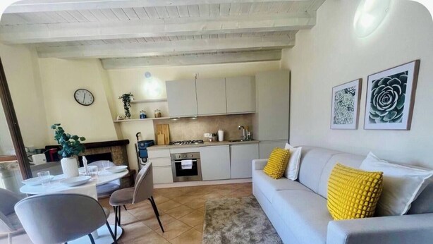 A modern living room with a grey sofa, a coffee table, and a dining area with chairs and a small table.