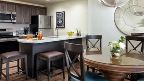 A modern kitchen with a central island, dark wooden chairs, and a glass dining table. - Bonita Springs 1BR Villa at Coconut Cove Near Gulf Beaches & Naples (Bonita Springs)