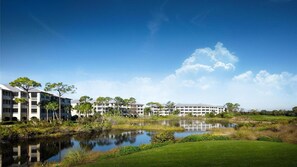 A modern hotel with a large building, a pond, and a well-maintained lawn. - Bonita Springs 1BR Villa at Coconut Cove Near Gulf Beaches & Naples (Bonita Springs)