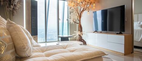 Une chambre moderne dotée d’un grand lit, d’un téléviseur à écran plat et offrant une vue sur la ville grâce à de grandes fenêtres.