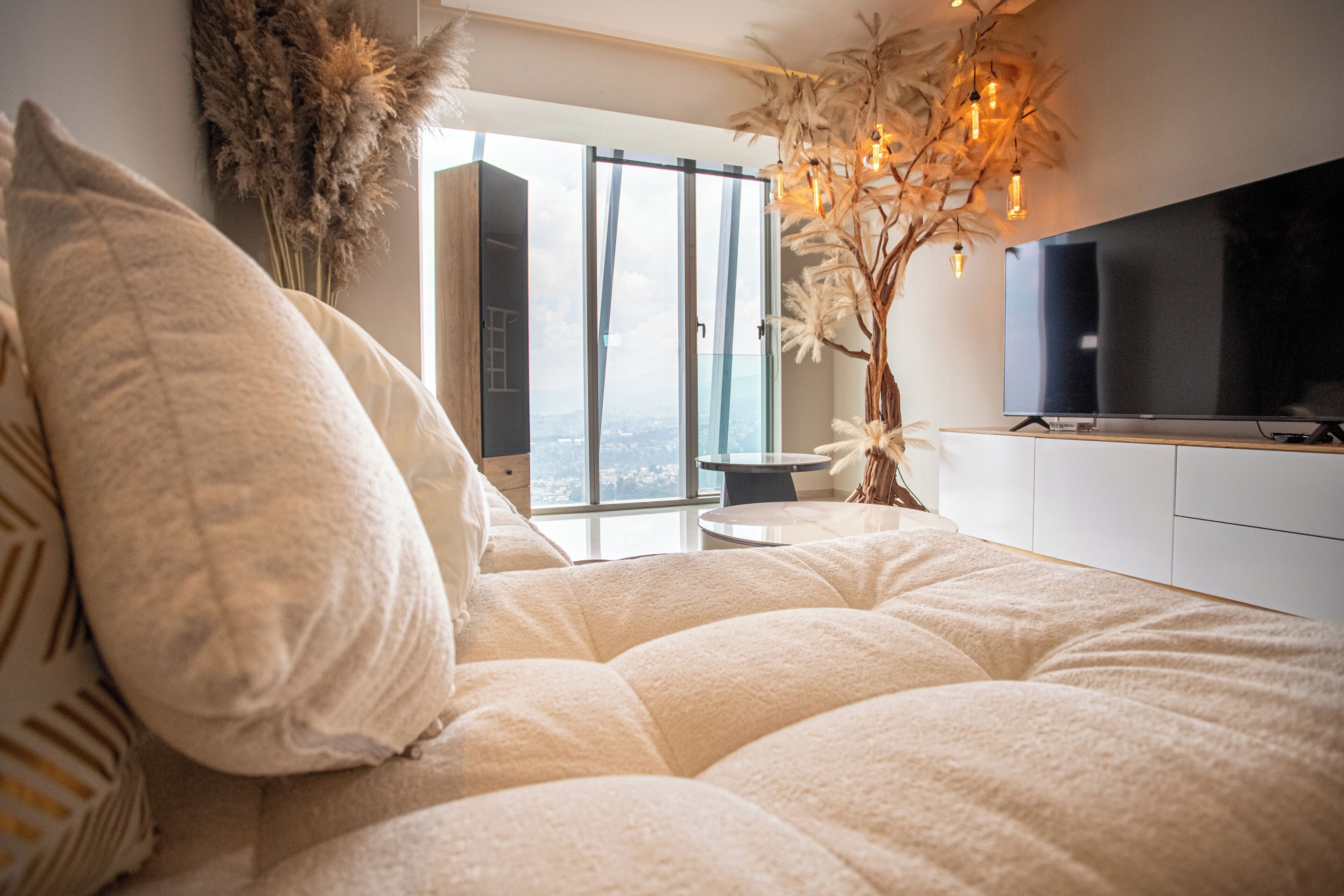 A bedroom with a large bed, a television, and a view of the city through the window.