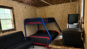 A compact room with a bunk bed, a sofa, and a small kitchenette.
