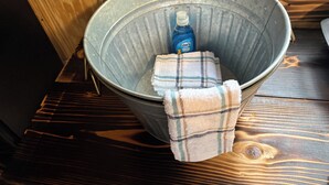 A metal bucket with a bottle of Dawn dish soap and a plaid towel inside.