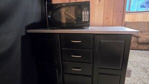 Eine kompakte Küchenzeile mit einer Mikrowelle, einem kleinen Schrank und einem an der Wand befestigten Feuerlöscher.