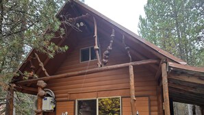 Eine rustikale Holzhütte mit Veranda, einer Schubkarre und einer Bank.