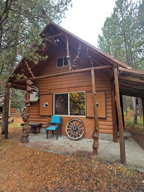 Eine rustikale Holzhütte mit Veranda, einer Schubkarre und einer Bank.