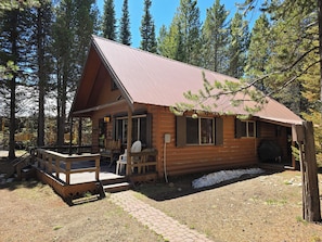 Une cabane en rondins dotée d’un porche, d’une terrasse et d’un espace extérieur couvert.