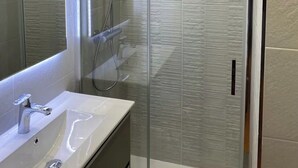 A modern bathroom with a glass-enclosed shower, a white sink, and a large mirror. - 
Central 2-Bedroom Apartment in Barcelona. (Barcelona)