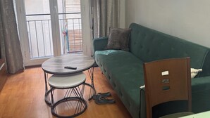 A living room with a green sofa, a round table, and a pair of slippers. - 
Central 2-Bedroom Apartment in Barcelona. (Barcelona)