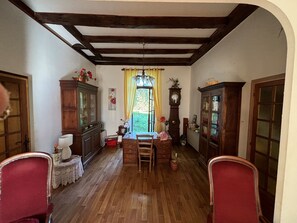 A room with wooden flooring, a dining table with chairs, a cabinet, and a large clock. - Country House for Rent (Lestrade-et-Thouels)