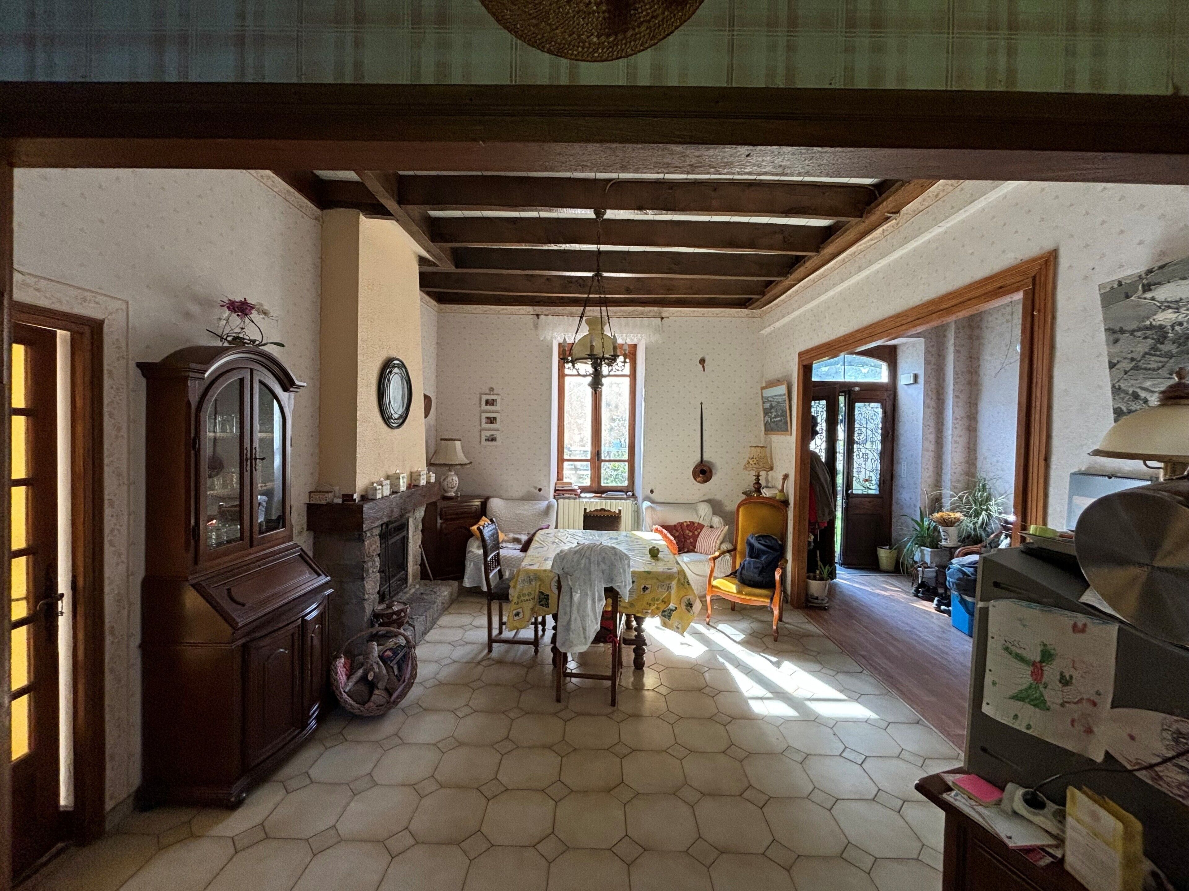Una habitación con suelo de baldosas hexagonales, un armario de madera, una mesa con sillas y una ventana con luz natural.