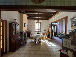 A room with a hexagonal tiled floor, a wooden cabinet, a table with chairs, and a window with natural light. - Country House for Rent (Lestrade-et-Thouels)
