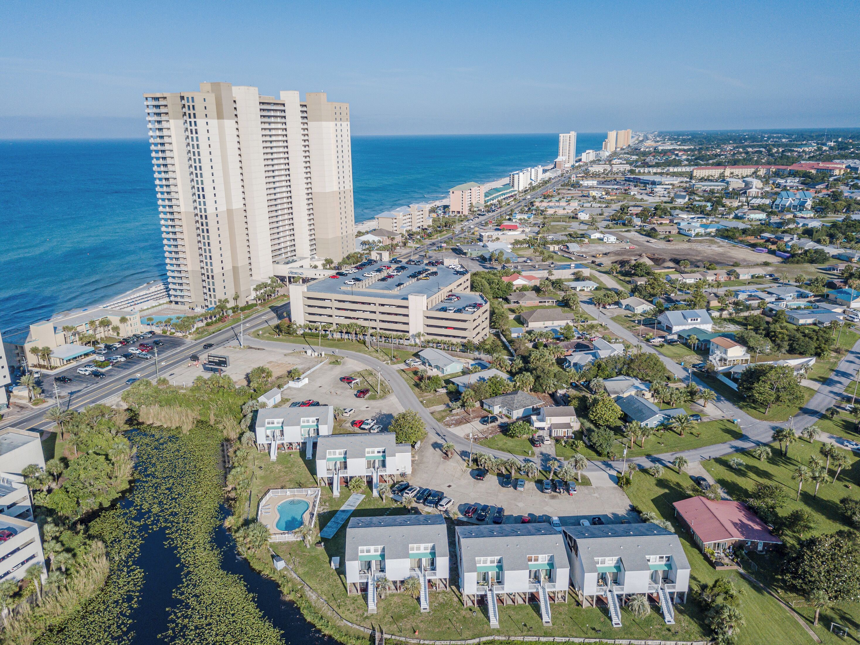 A coastal residential area with high-rise buildings, a marina, and a parking lot.