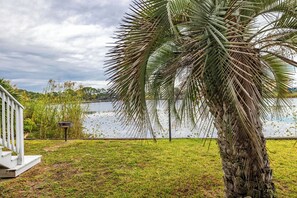 A grassy area with a palm tree and a body of water in the background. - Turtle House - Quiet 2BR 2BA - Seconds from beach, short walk to Pier Park. (Panama City Beach)