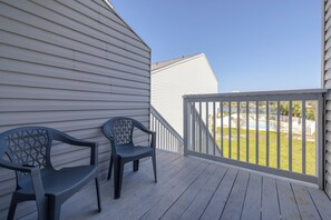 A wooden deck with two chairs and a railing overlooking a grassy area. - Turtle House - Quiet 2BR 2BA - Seconds from beach, short walk to Pier Park. (Panama City Beach)