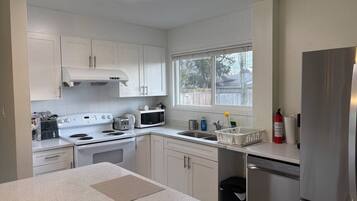 A modern kitchen with white cabinets, stainless steel appliances, and a window providing natural light.