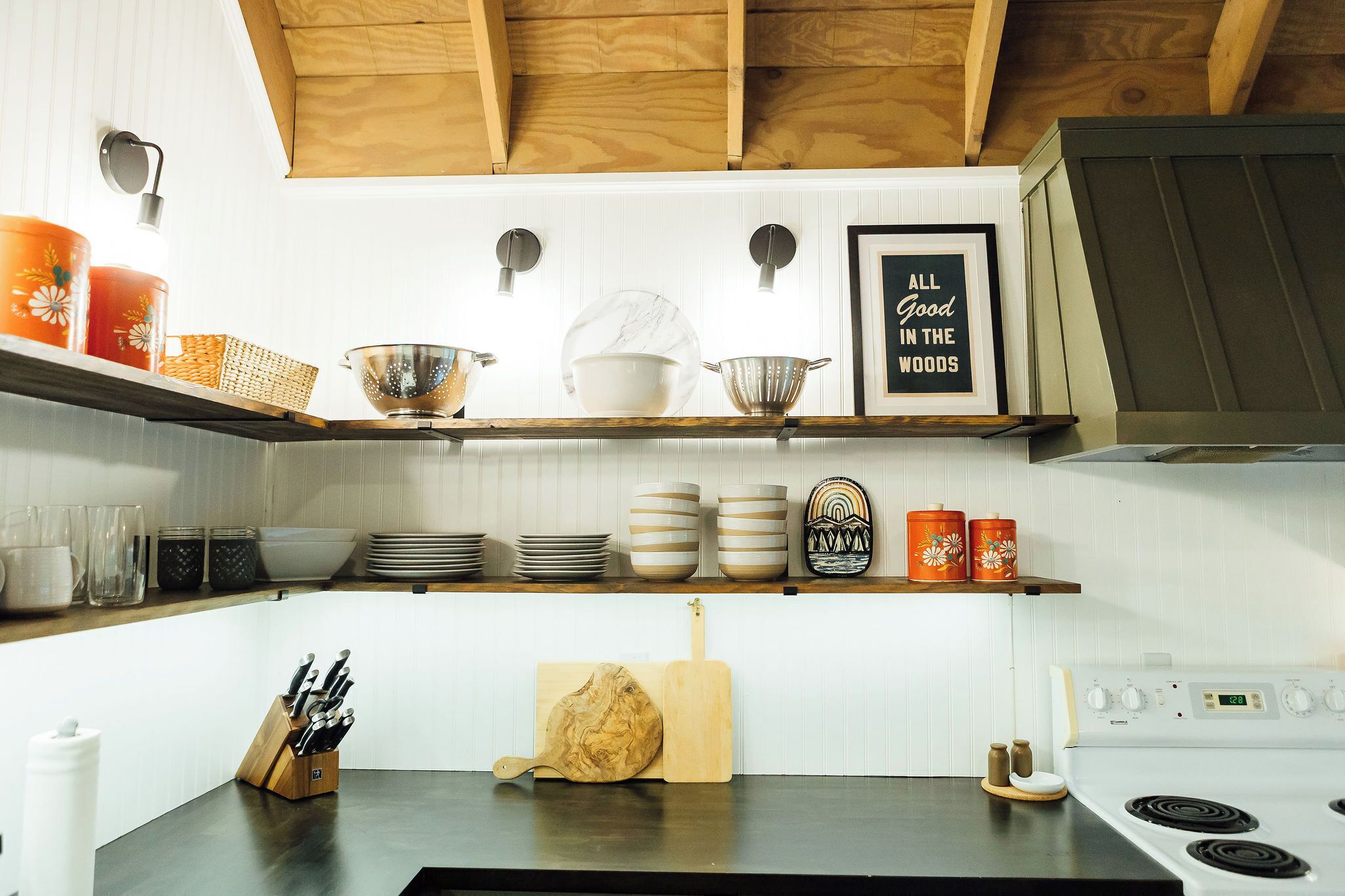 A kitchen with wooden beams, white cabinets, and various kitchenware.