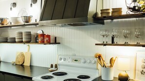 Una cocina con estufa blanca, armarios de madera y techo de madera.