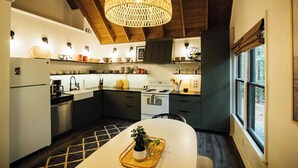 Una cocina moderna con una isla central, vigas de madera en el techo y un ventanal grande.