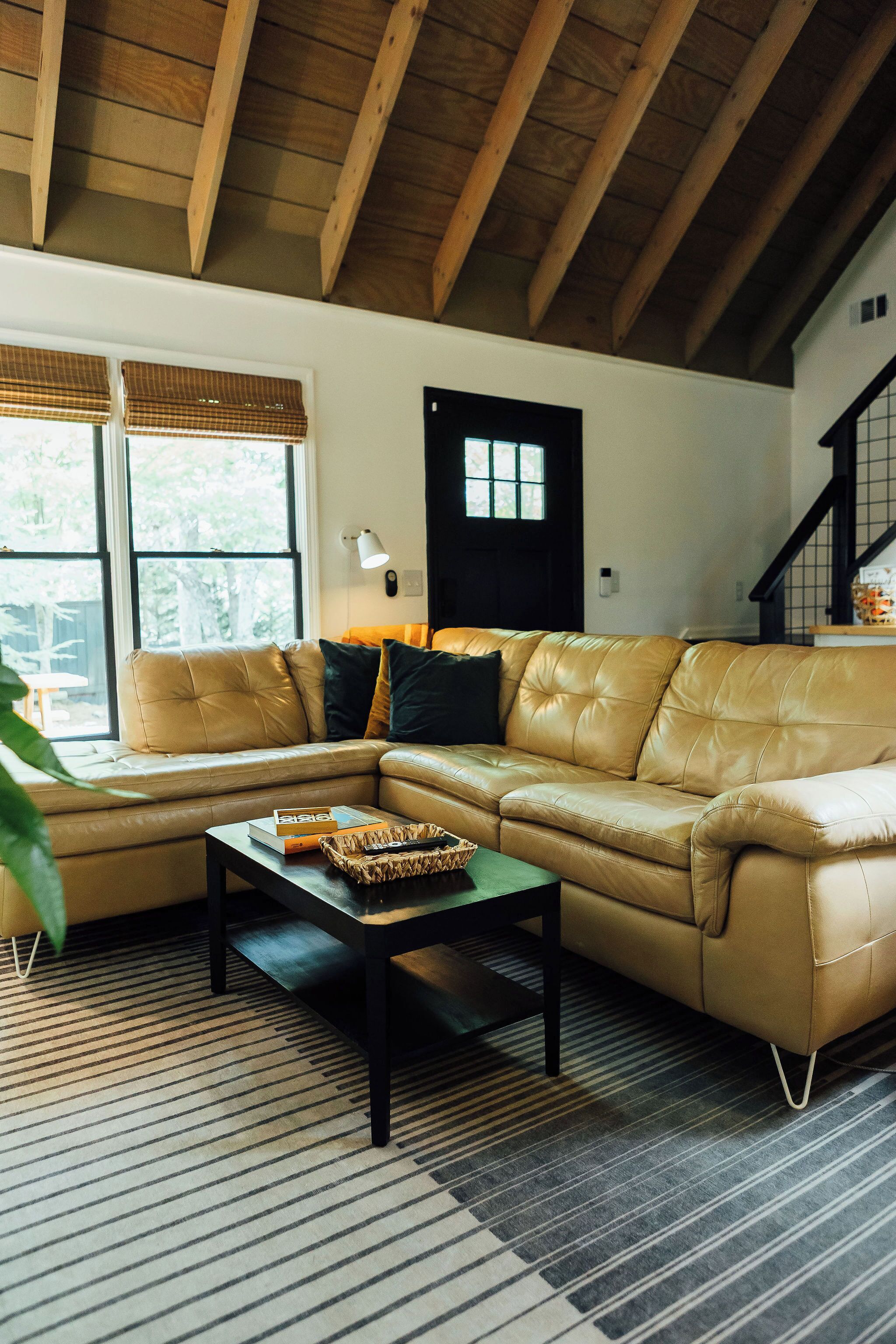 Ein Wohnzimmer mit Ecksofa, Couchtisch und einem Fenster mit Jalousien.