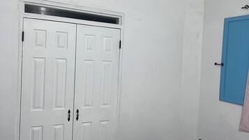 Une chambre avec un lit, une armoire blanche et un ventilateur de plafond.