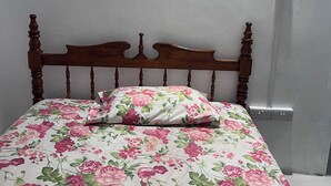 A bed with a floral bedspread and a wooden headboard.