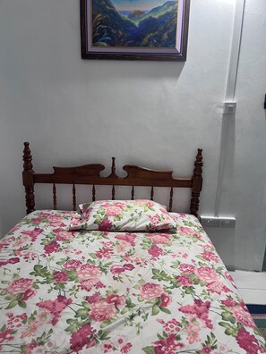 A bed with a floral bedspread and a wooden headboard.