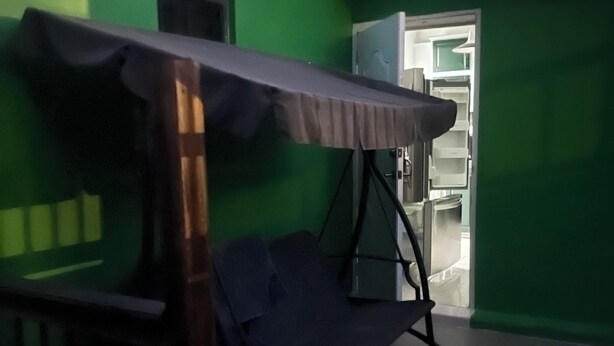 A room with a green wall, a bed with a canopy, and a door leading to a bathroom.