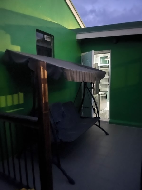 A room with a green wall, a bed with a canopy, and a door leading to a bathroom.