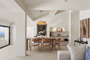 A modern dining area with a wooden table and chairs, a hanging light fixture, and a view of the sea through a balcony door. - Across from the harbor • 3 bedrooms • Saint-Tropez (Saint-Tropez)