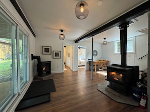 A modern living room with a fireplace, wooden flooring, and large windows.