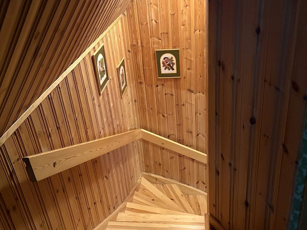 A wooden staircase with a handrail, wooden walls, and framed pictures. - 4 Person Holiday Home in Hassela (Hassela)