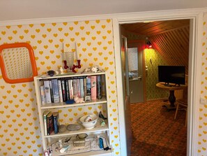 Une pièce avec une bibliothèque, un téléviseur et un mur orné d’un motif.