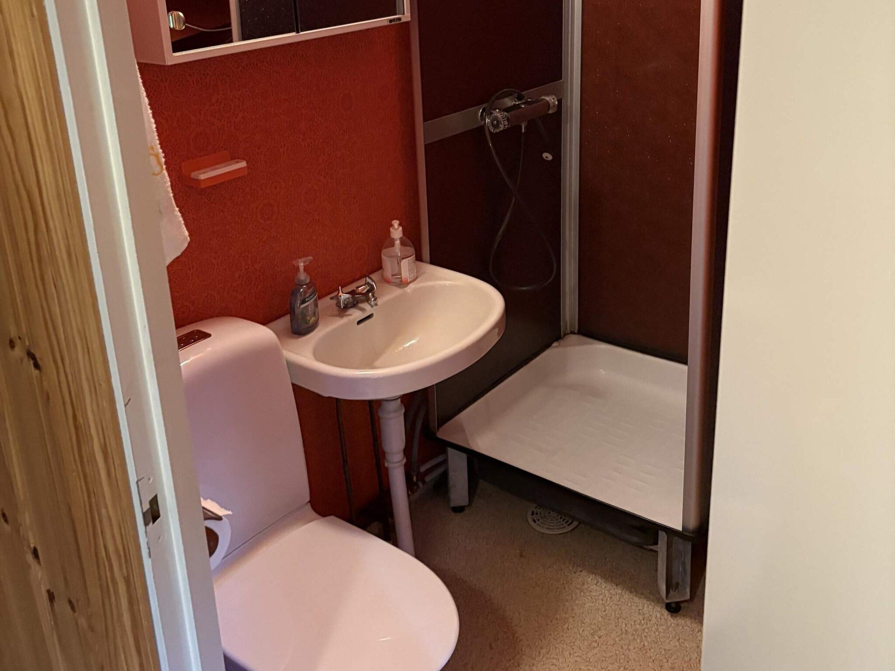 A small bathroom with a white toilet, a sink, and a shower stall.