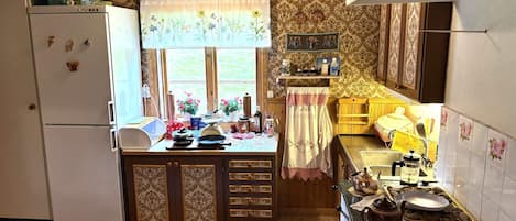 Une cuisine de taille réduite, équipée d’un réfrigérateur, d’une cuisinière et de meubles de rangement en bois.