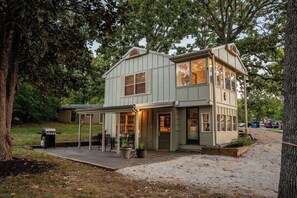 Une maison à deux étages dotée d’un patio couvert et d’un barbecue.