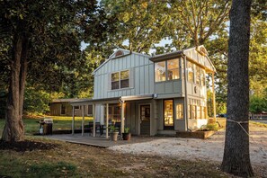 A two-story house with a covered patio, a barbecue grill, and potted plants. - Magnolia House Retreat at Stillwaters Resort (Branson)