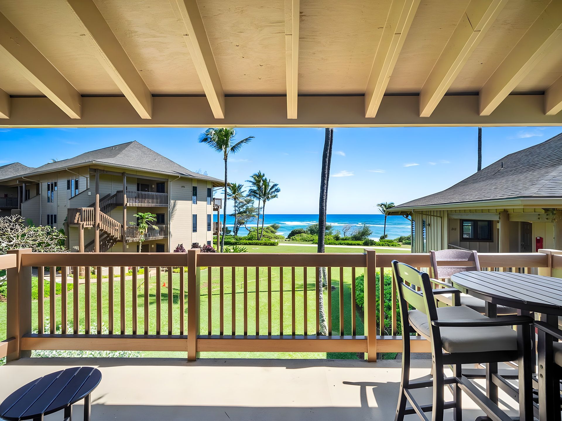 A covered outdoor area with a view of the ocean and a building with a balcony.