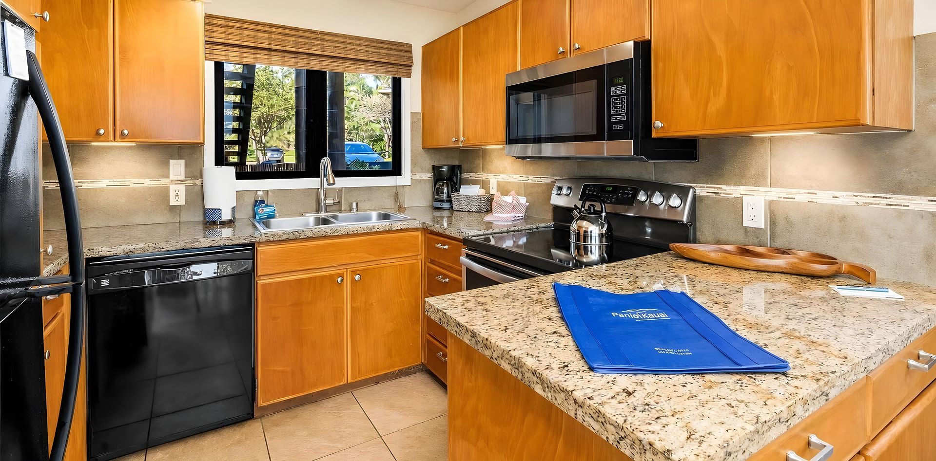A modern kitchen with wooden cabinets, a stainless steel microwave, a dishwasher, and a granite countertop.