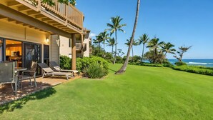 A beachfront property with a pool, lounge chairs, and a view of the ocean. - Breezy 4BR, 2 Condos for 12 at Kaha Lani, Lihue! (Lihue)