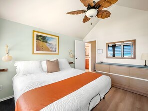 A bedroom with a bed, a window with curtains, a ceiling fan, and a painting on the wall.