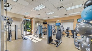 Ett gym med olika typer av träningsredskap, en dörr som leder ut och en klocka på väggen.