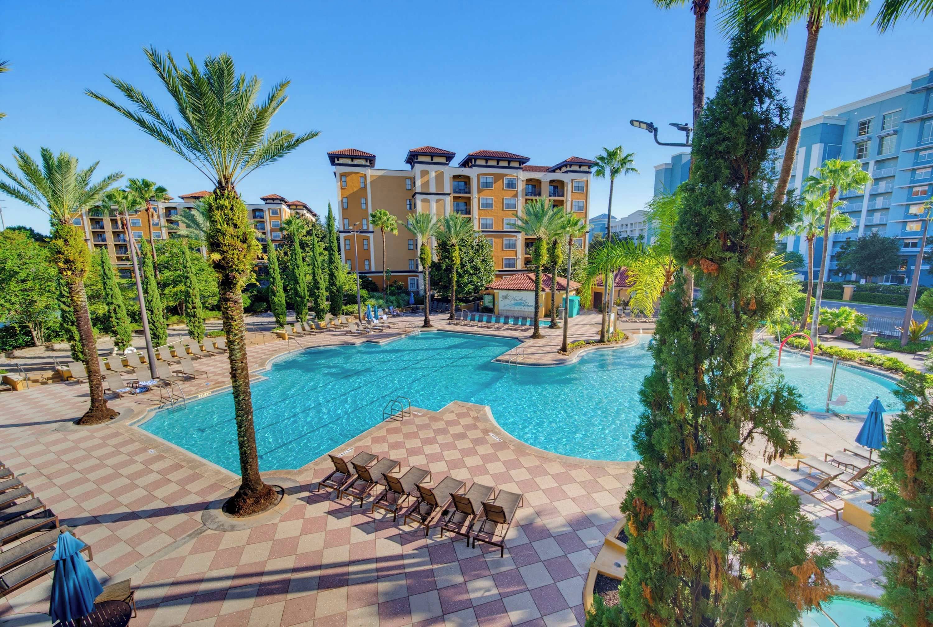 A hotel pool area with multiple lounge chairs and a large central pool.