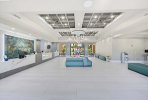 Eine großzügige Lobby mit einer Rezeption, einer Sitzecke und Blick ins Freie.